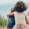 Dos niñas abrazadas frente al mar